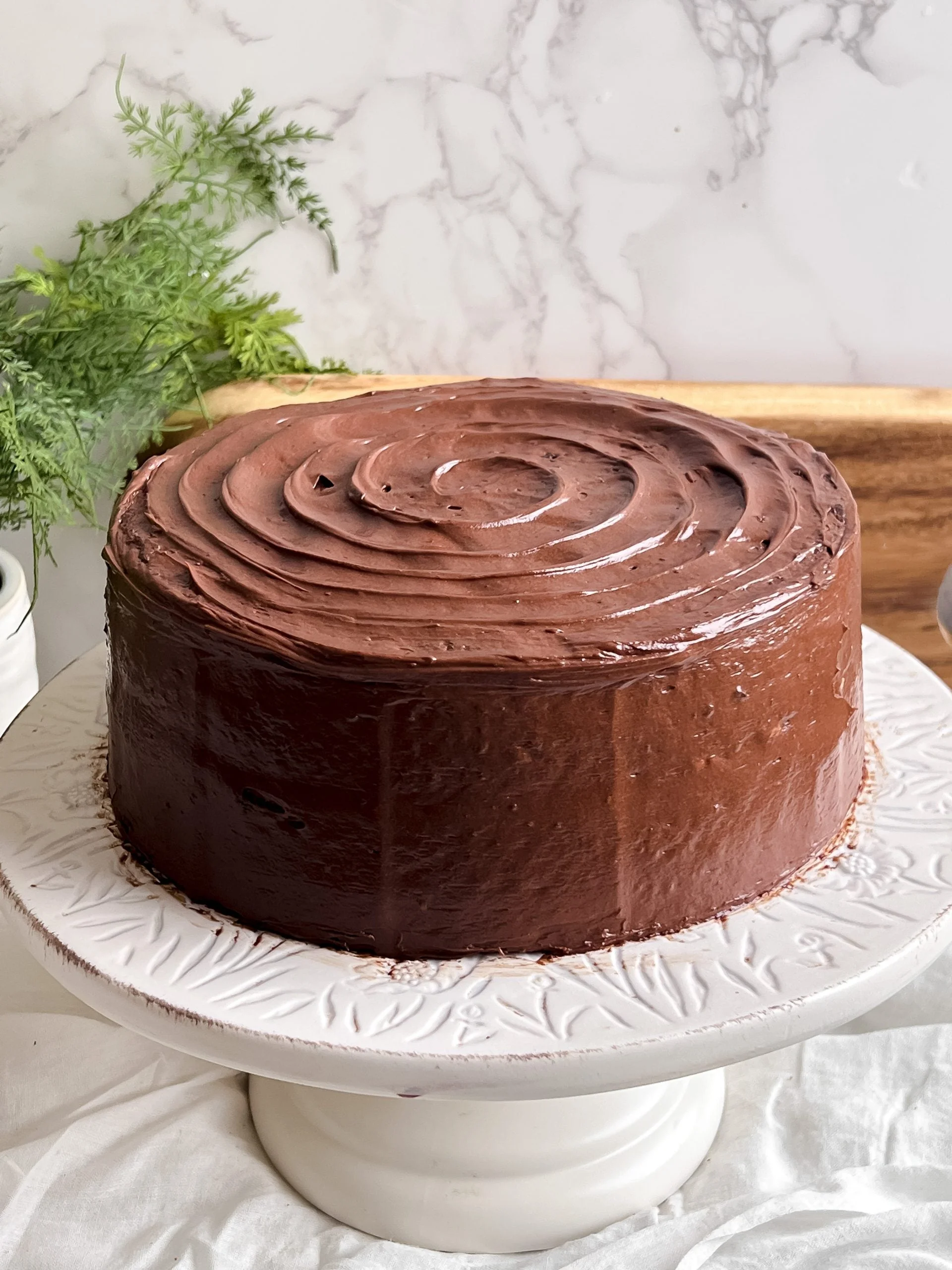 Bánh chocolate tròn phủ kem xoáy trên chân đế trắng