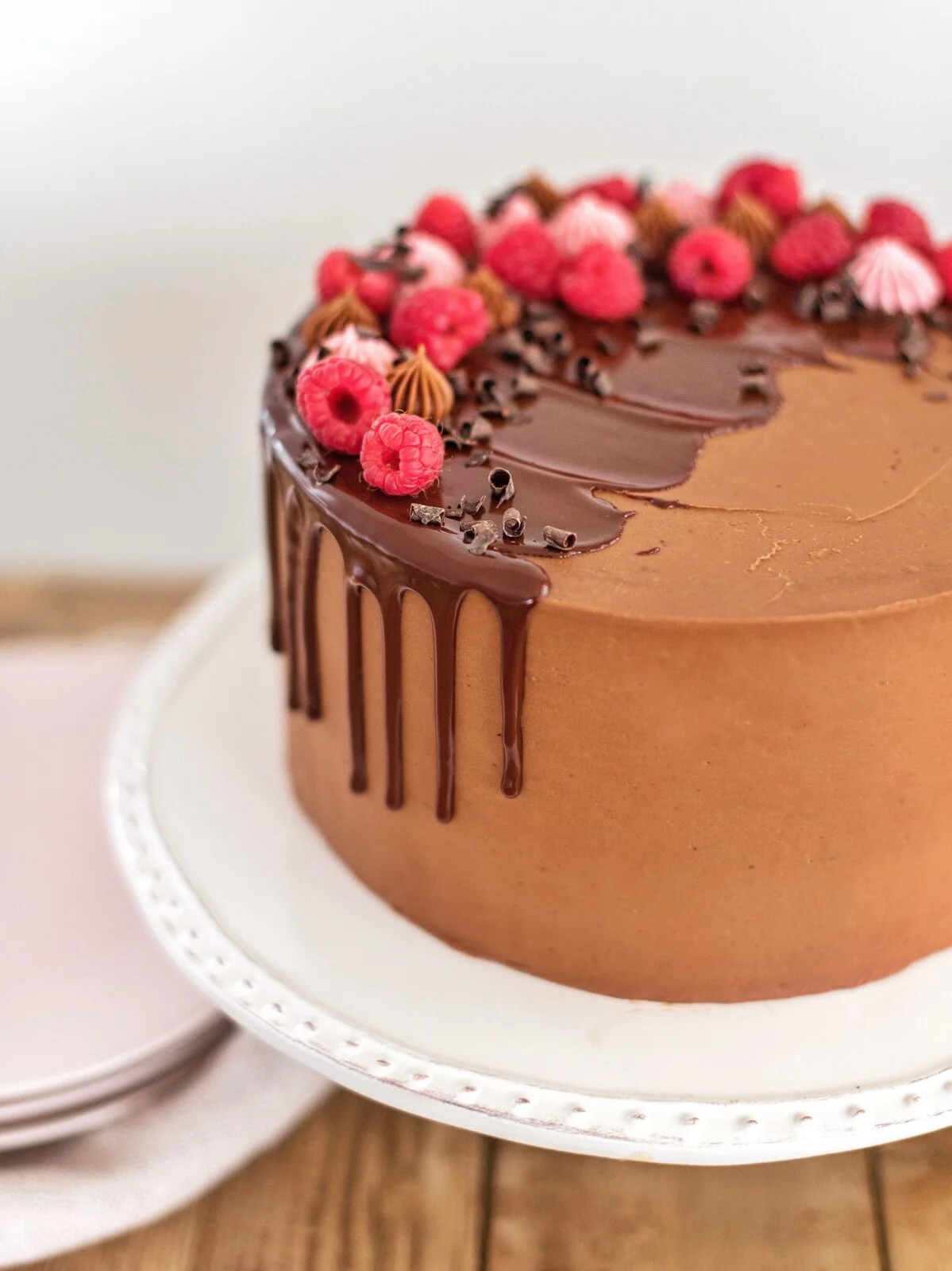 Bánh kem chocolate trang trí hoa đỏ trên đĩa trắng