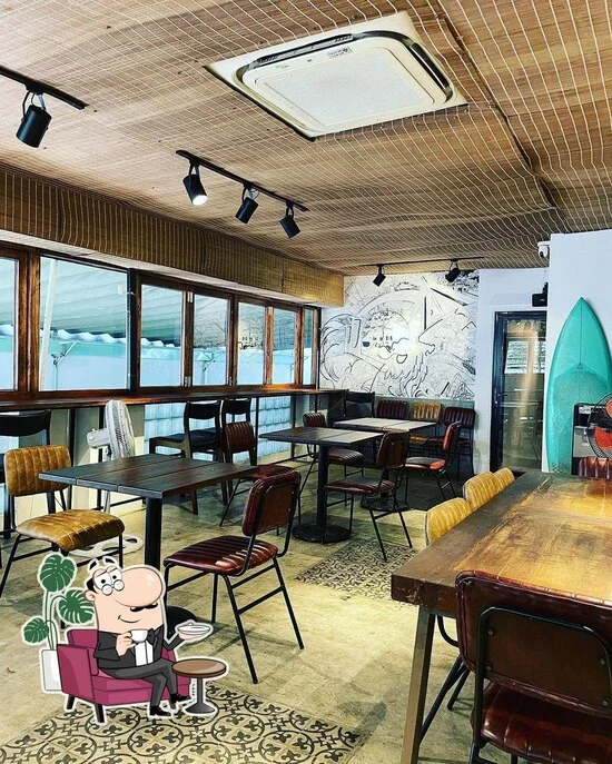 Không gian quán Bikini Bottom Express với bàn gỗ, ghế nhiều màu và tranh tường chủ đề biển