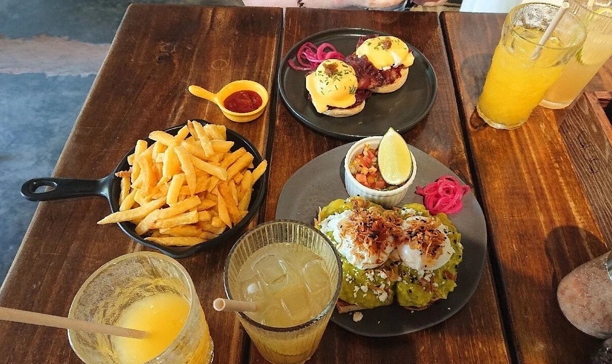 Bữa ăn đa dạng với burger, khoai tây chiên, salad và đồ uống trên bàn gỗ